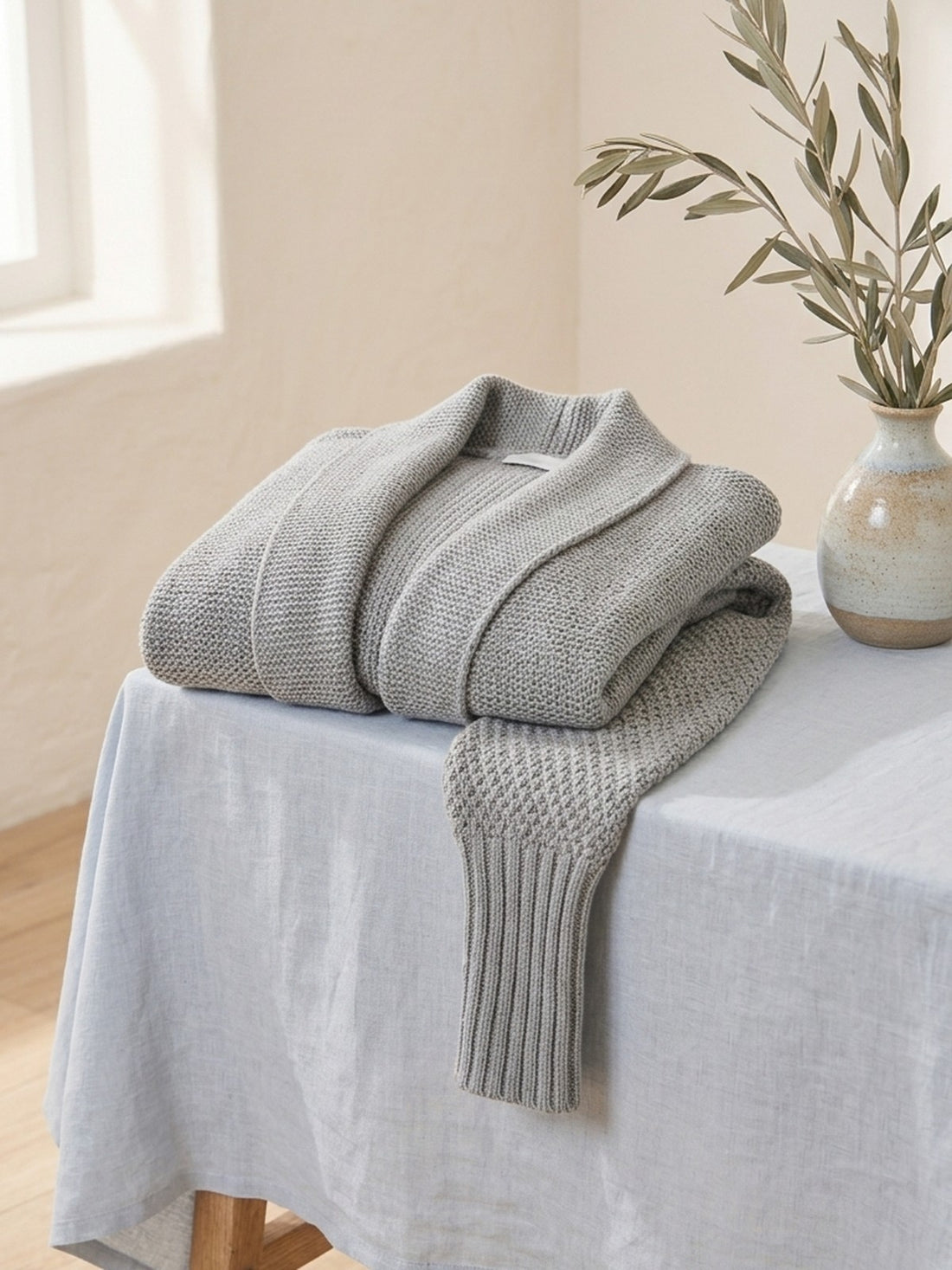 Chunky Batwing Cardigan folded on a stool, showing the knit texture and ribbed cuff