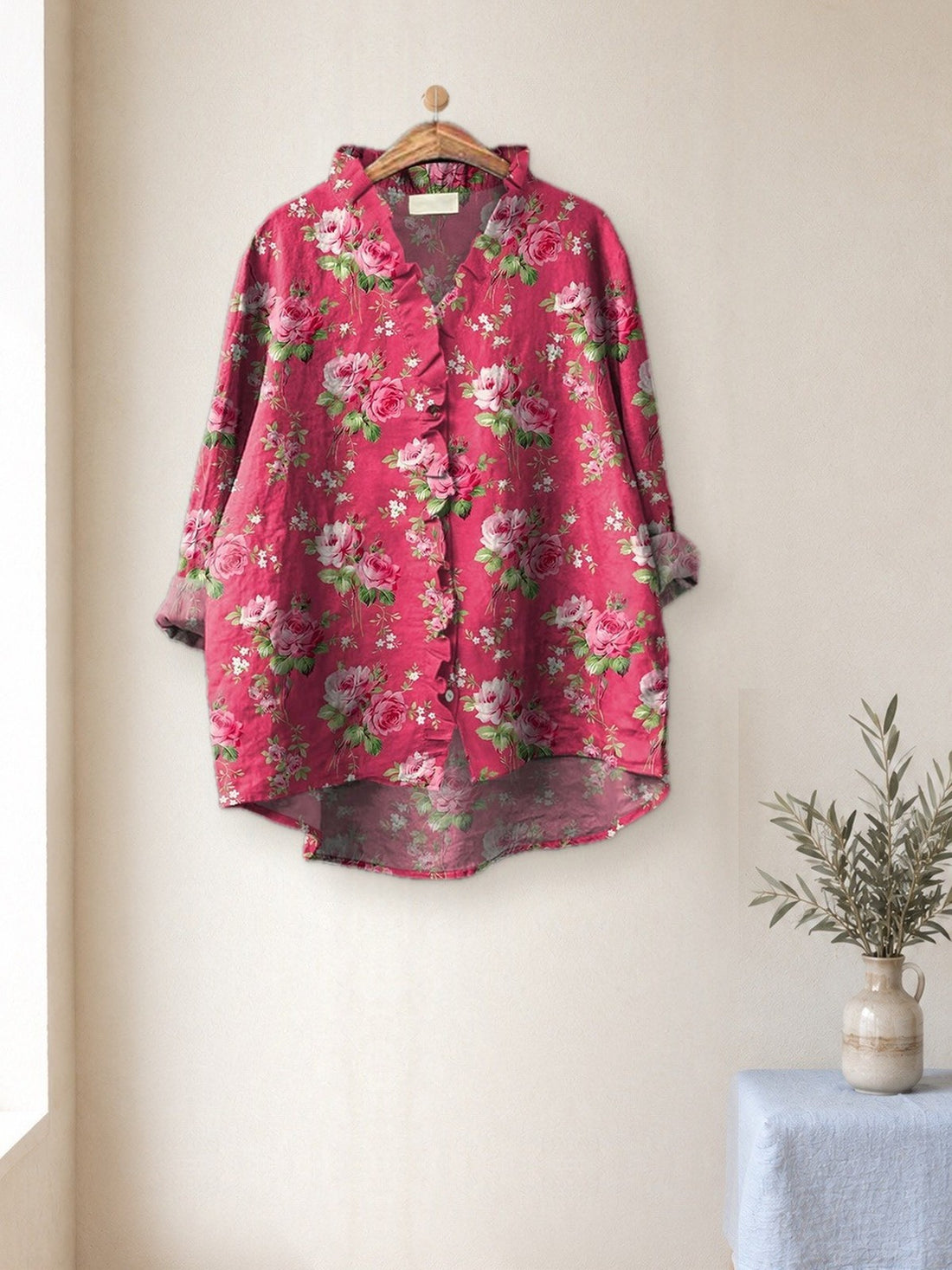 Fuchsia Floral Ruffle Shirt hanging in a bright studio