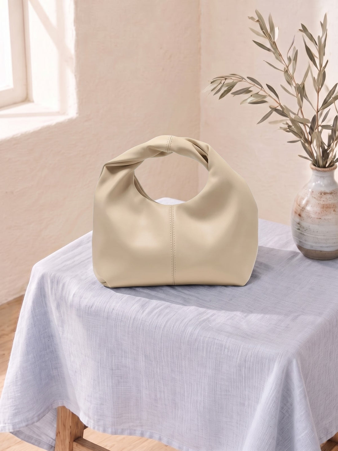 Soft Pouch Handbag on a linen-covered stool