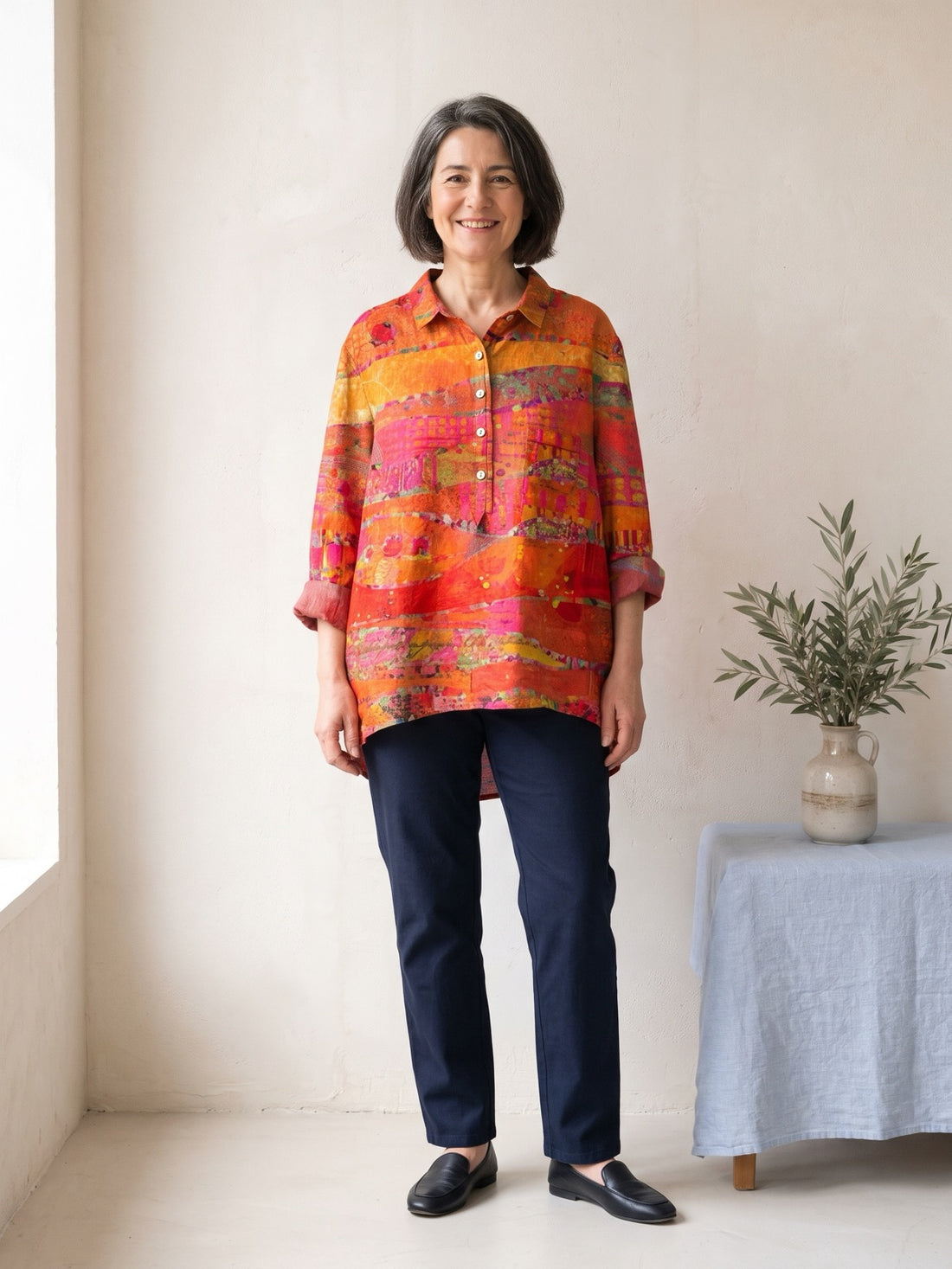 Woman in her fifties wearing the Orange Abstract Print Shirt with navy trousers