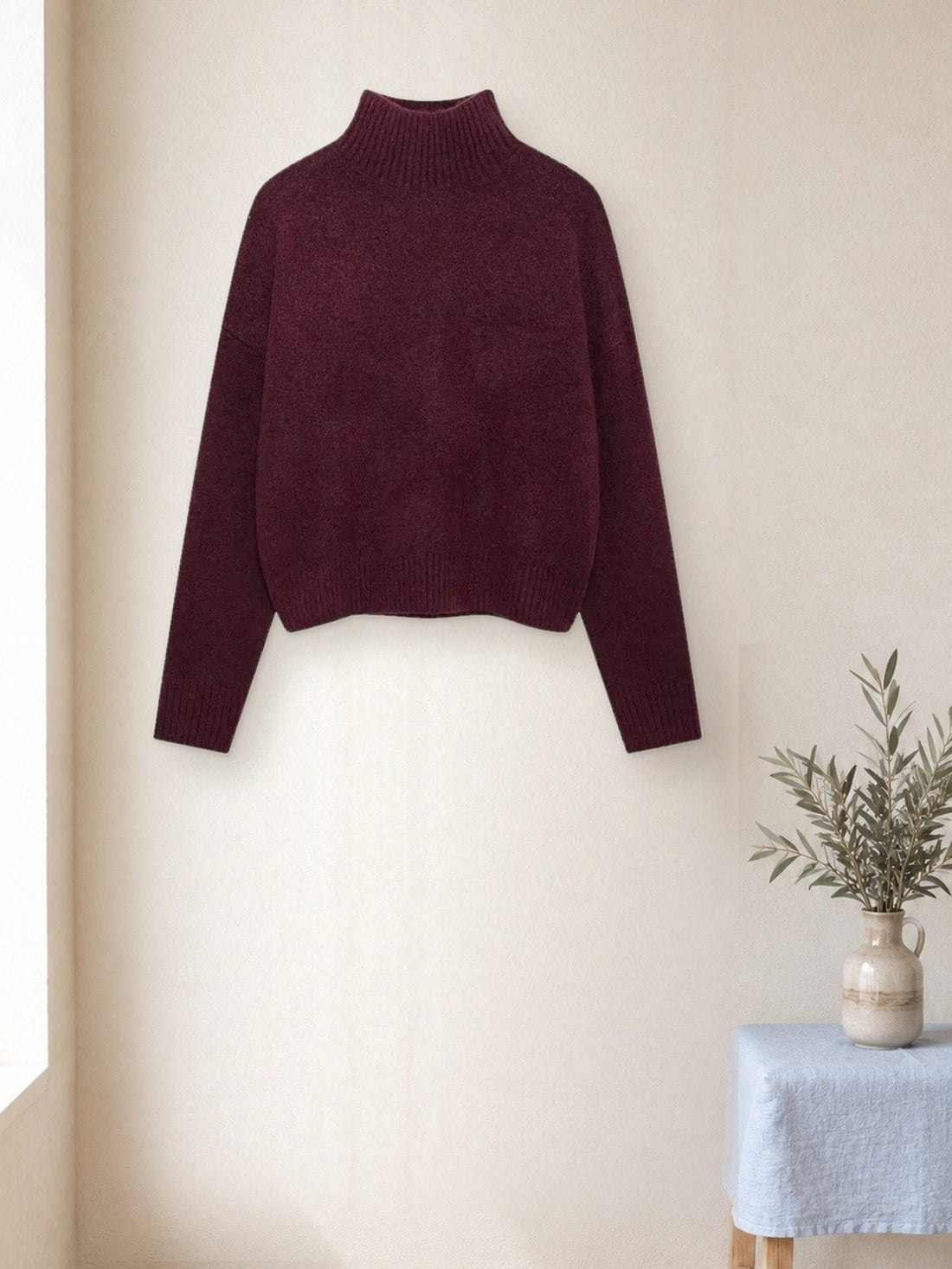 Relaxed Turtleneck Jumper hanging in a bright studio