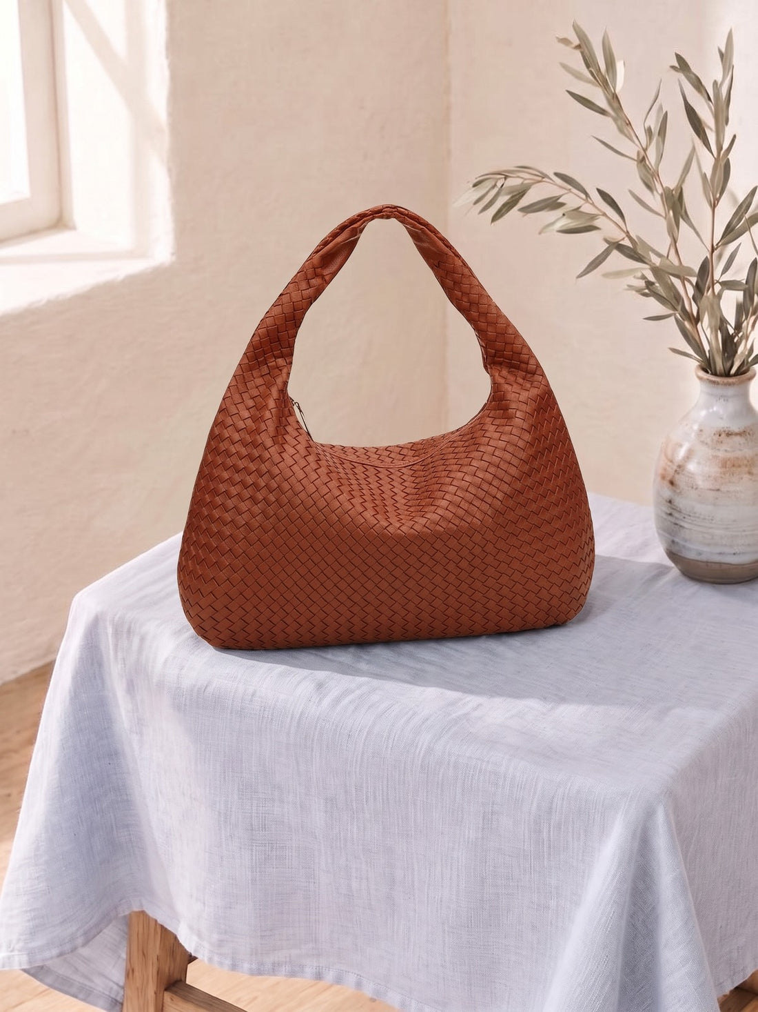 Woven Hobo Shoulder Bag on a linen-covered stool