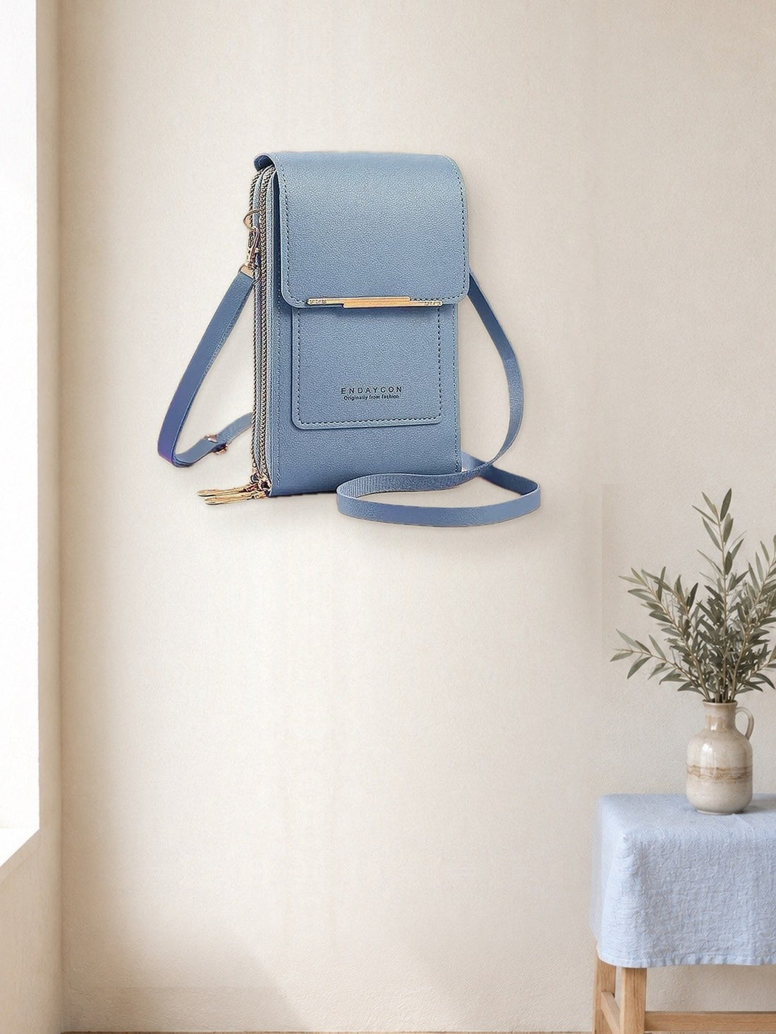 Touchscreen Phone Crossbody Bag hanging in a bright studio