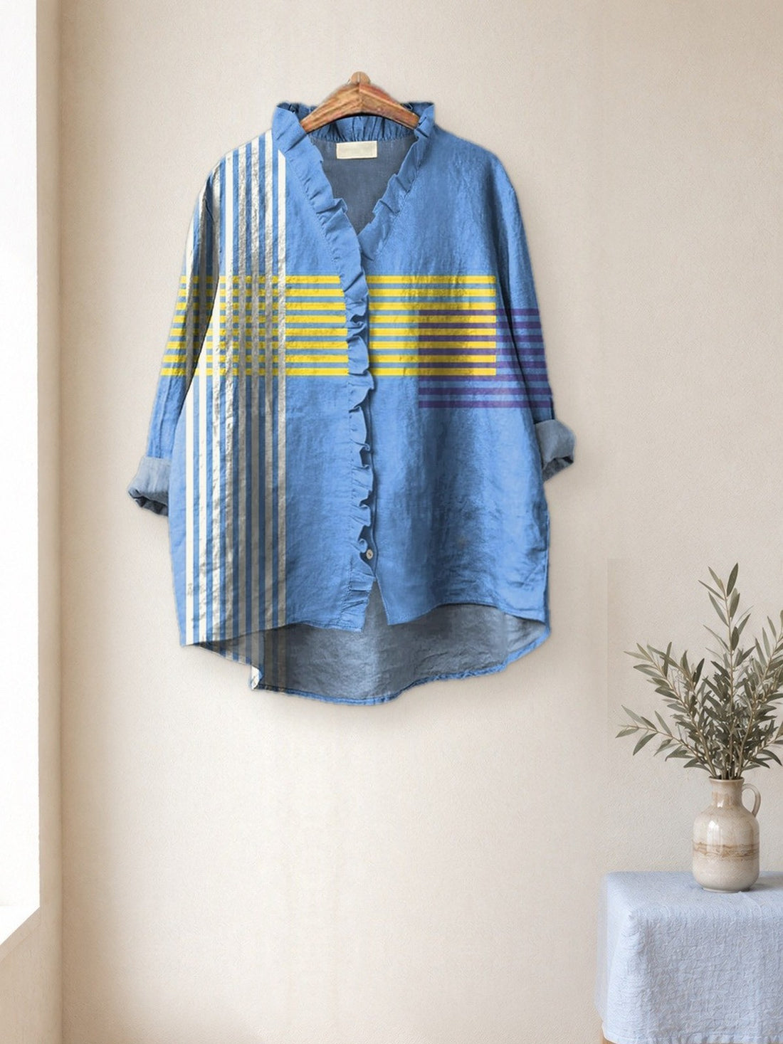Blue Striped Ruffle Shirt hanging in a bright studio
