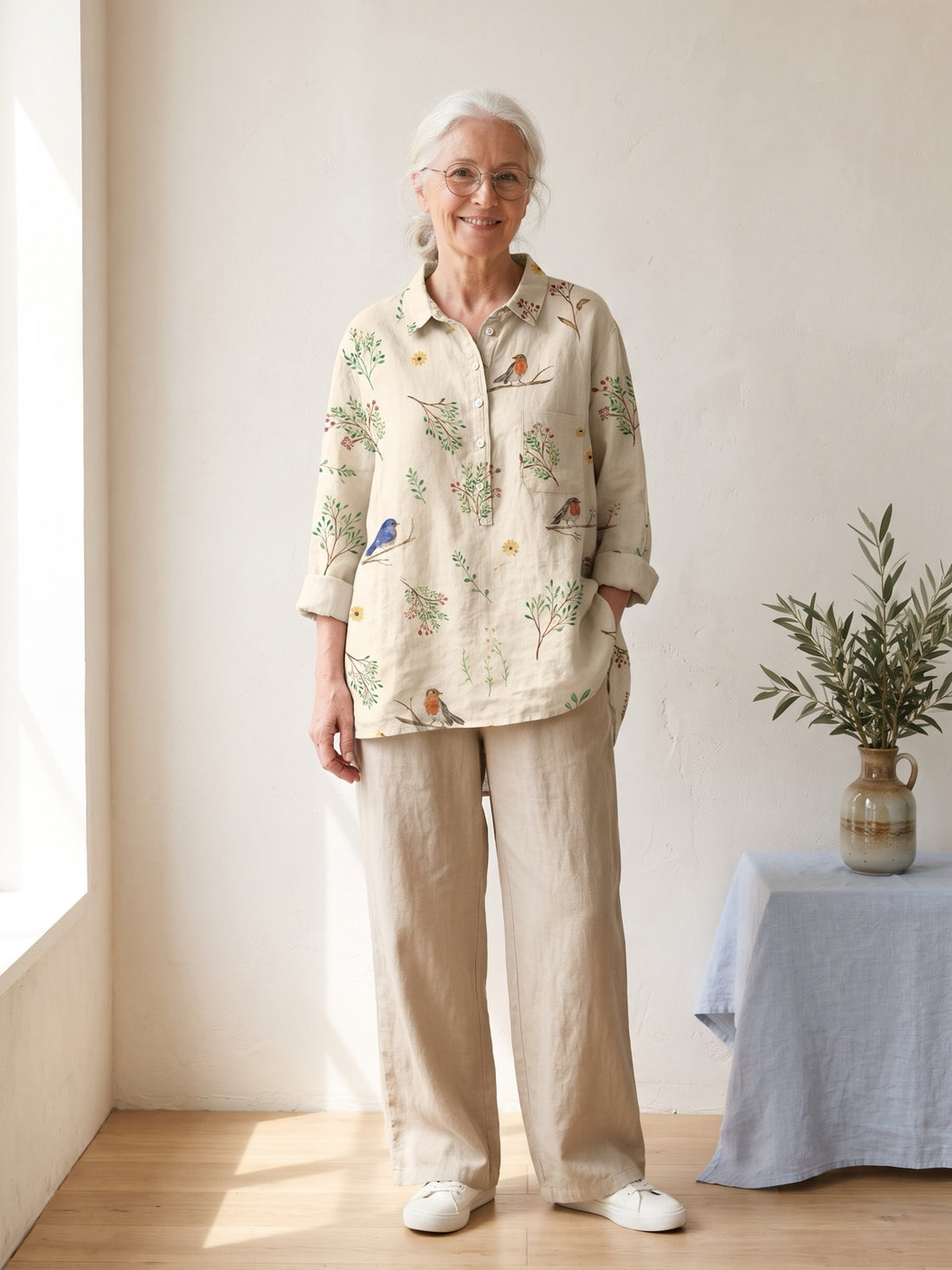 Woman around sixty wearing the Cream Botanical Bird Shirt with beige trousers