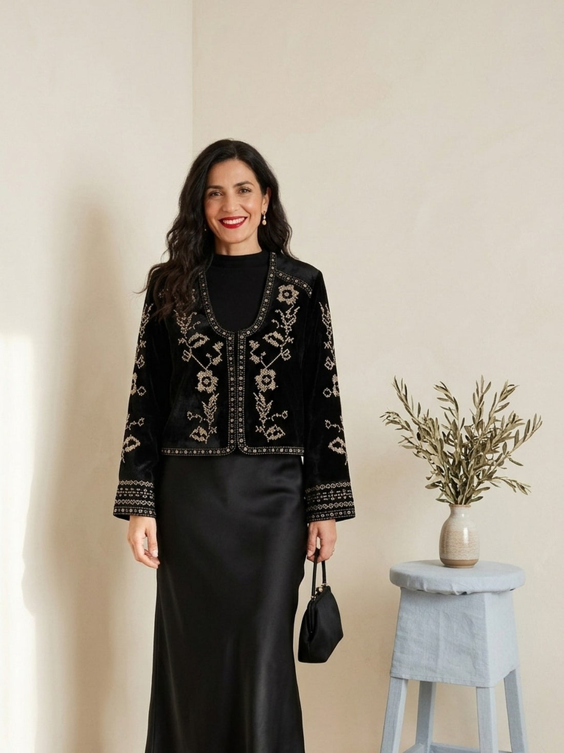 Woman in her forties wearing the black Embroidered Velvet Cropped Jacket with a satin skirt