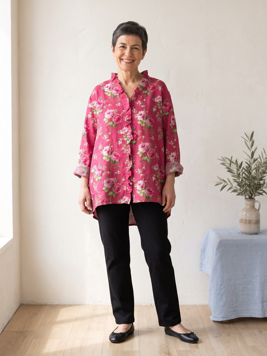 Woman in her fifties wearing the Fuchsia Floral Ruffle Shirt with black trousers