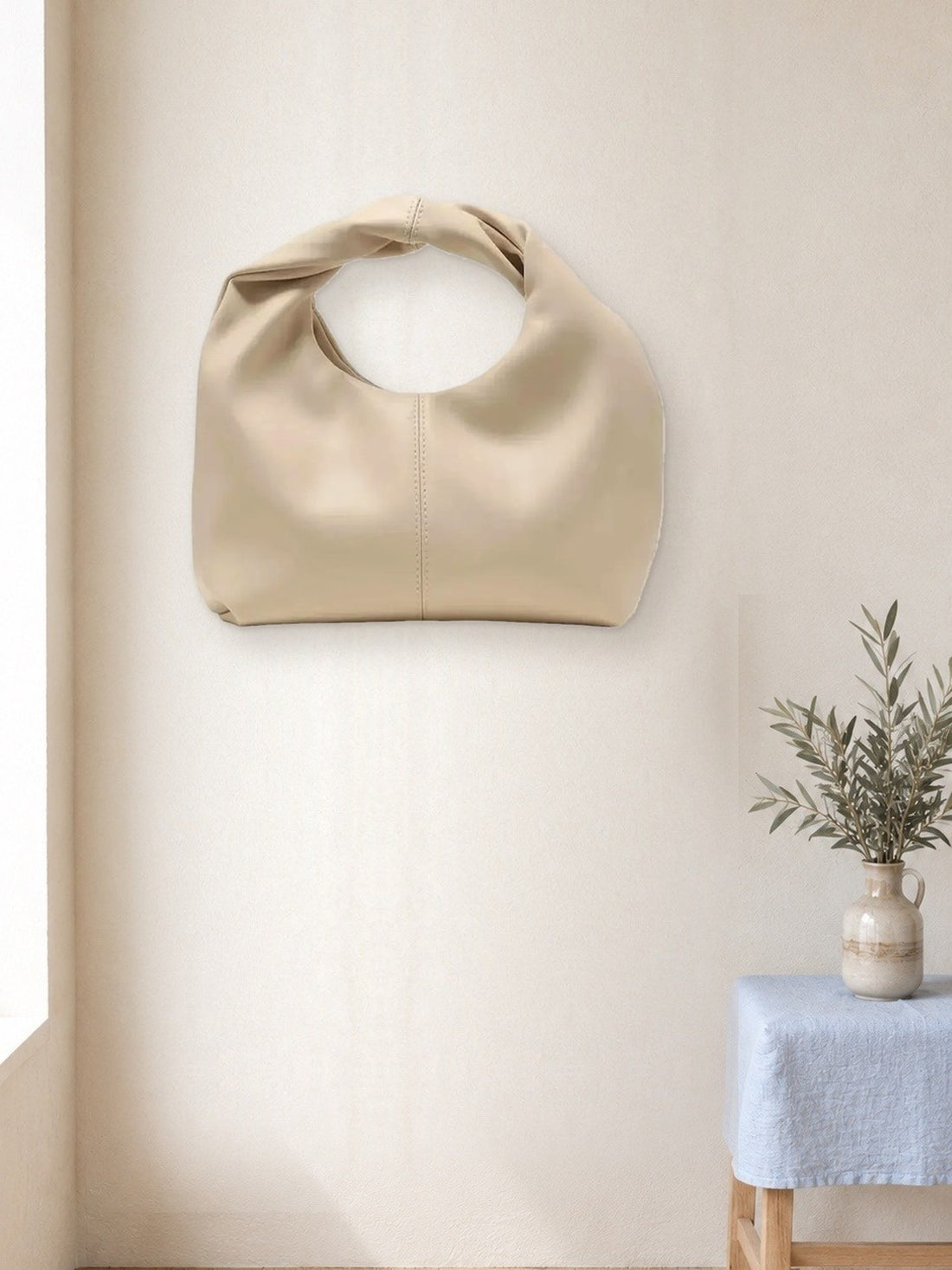 Soft Pouch Handbag hanging in a bright studio