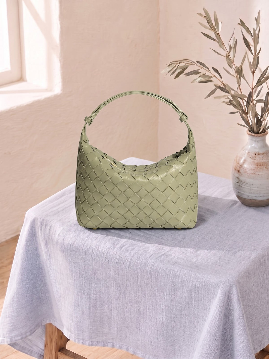 Mini Woven Top-Handle Bag on a linen-covered stool