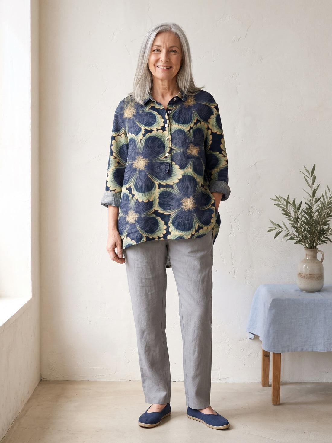 Woman in her late fifties wearing the Navy Bold Flower Shirt with grey trousers