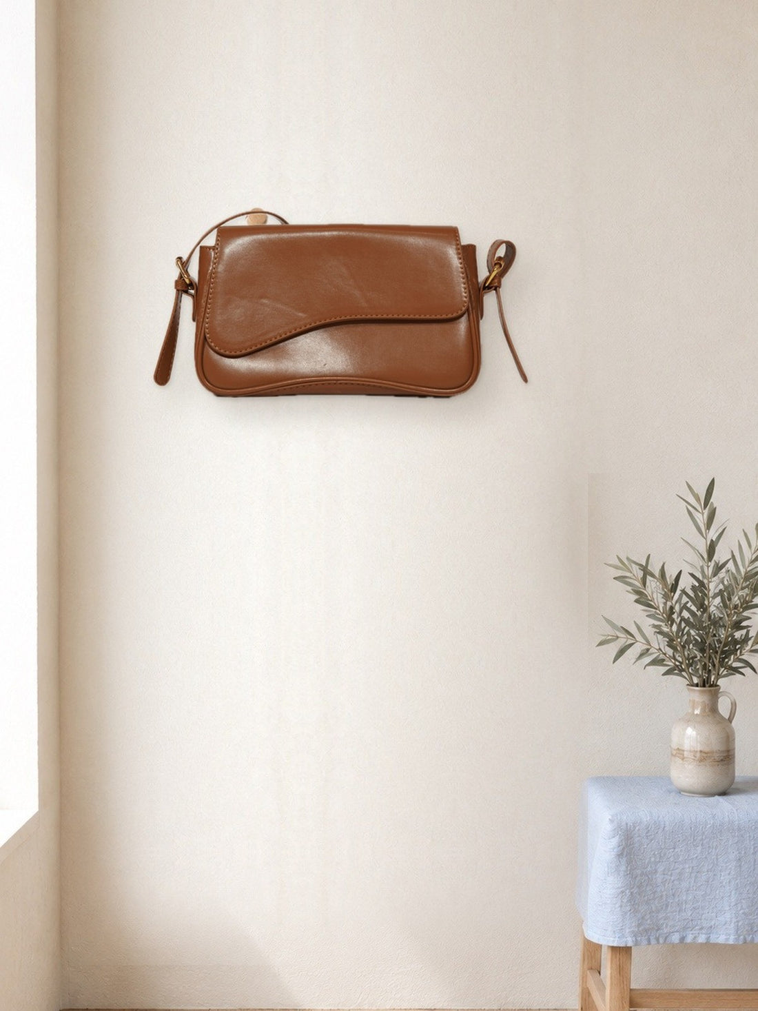 Flap Crossbody Bag hanging in a bright studio