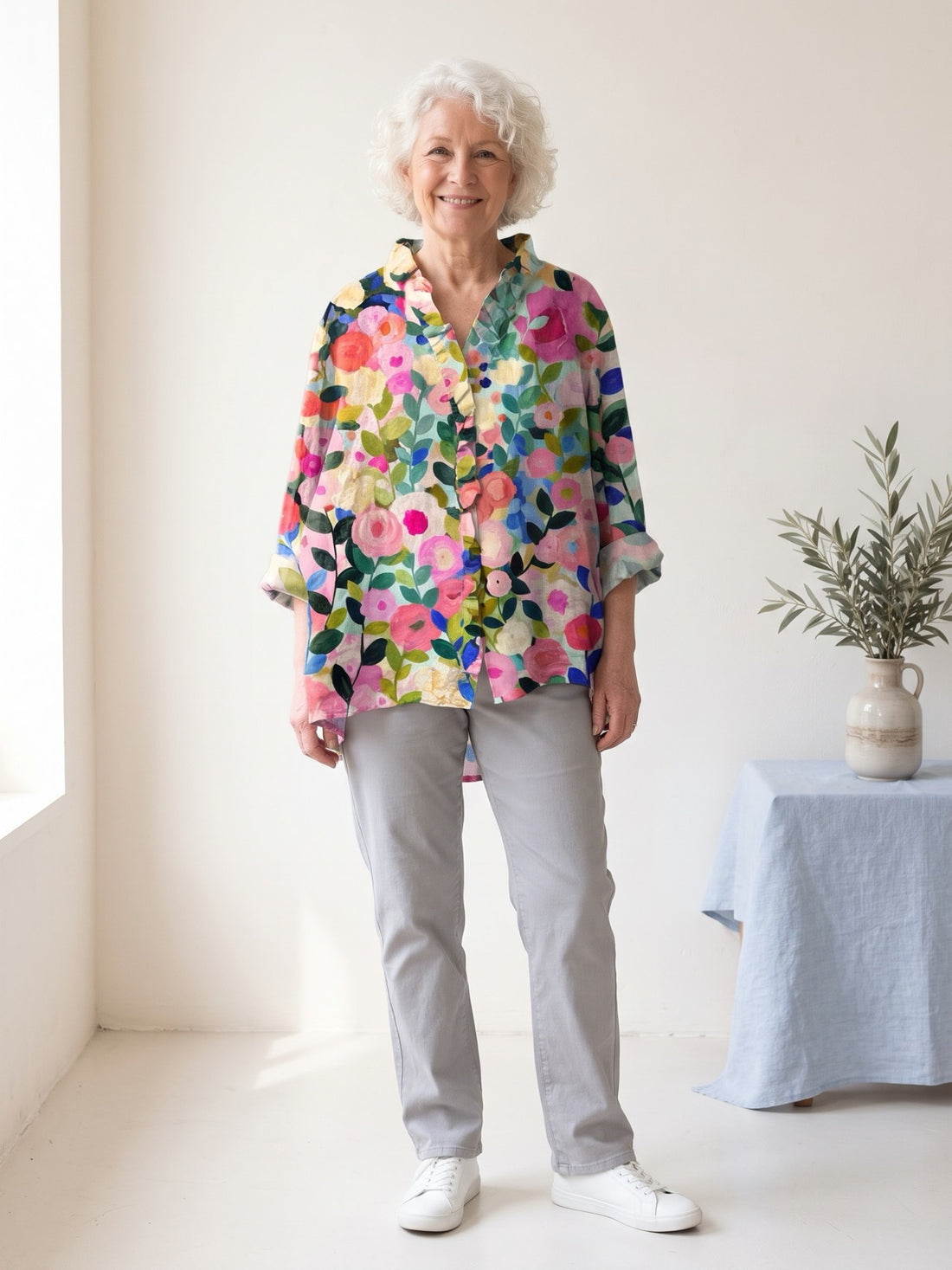 Woman in her sixties wearing the Pastel Floral Garden Shirt with grey trousers