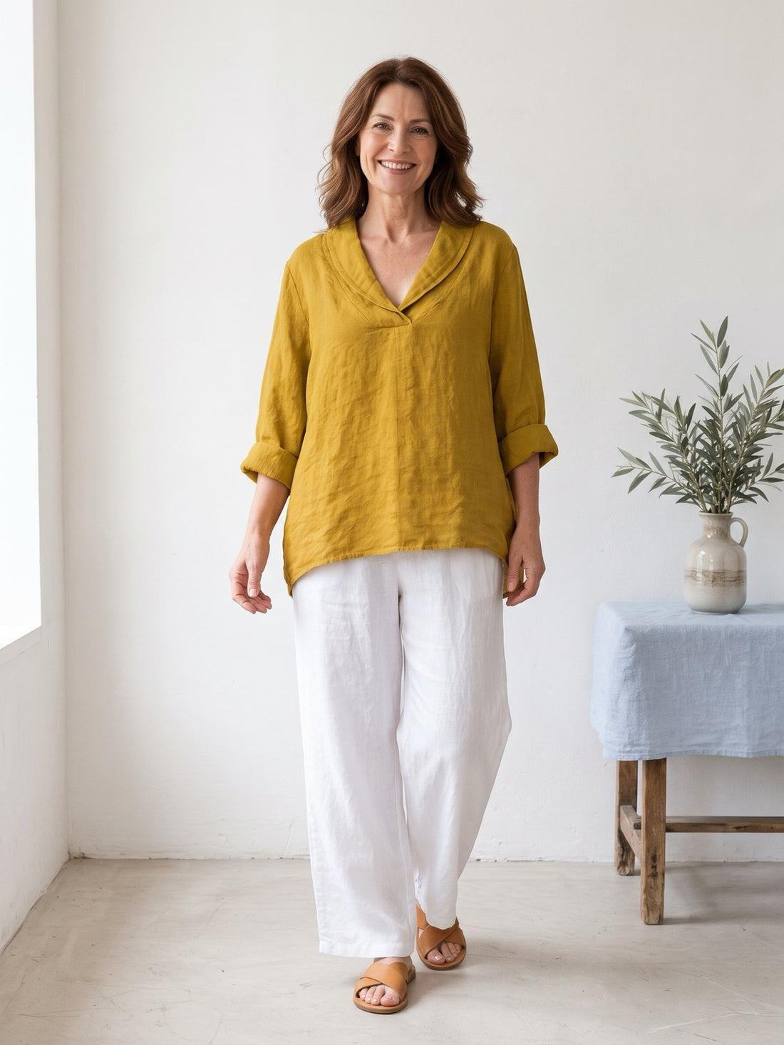 Woman in her fifties wearing the Relaxed V-Neck Linen-Look Top in yellow with white trousers