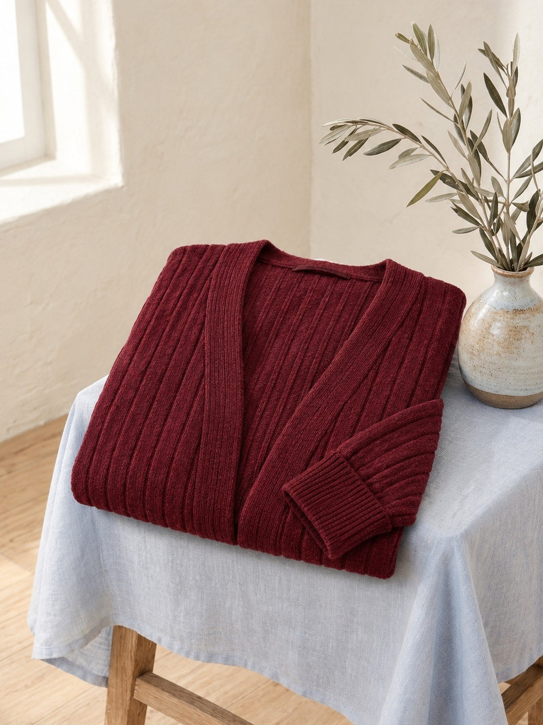 Ribbed Open Cardigan folded on a stool, showing the rib knit and cuff
