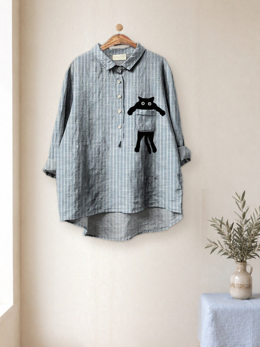 Striped Cat Pocket Shirt hanging in a bright studio