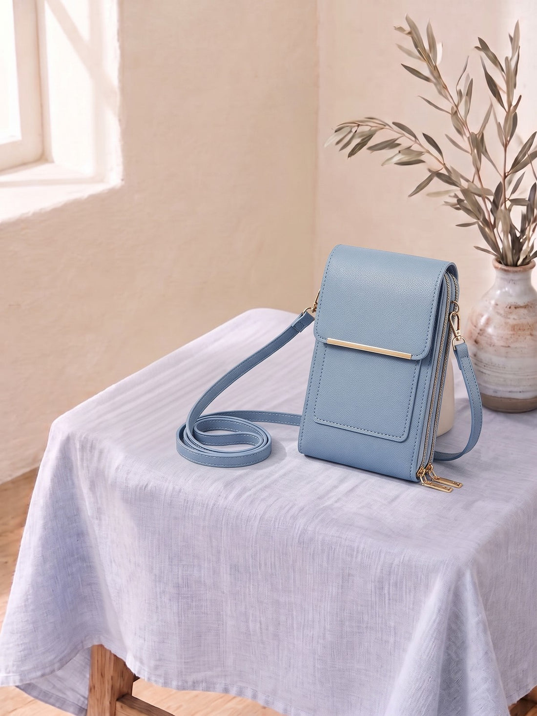 Touchscreen Phone Crossbody Bag on a linen-covered stool